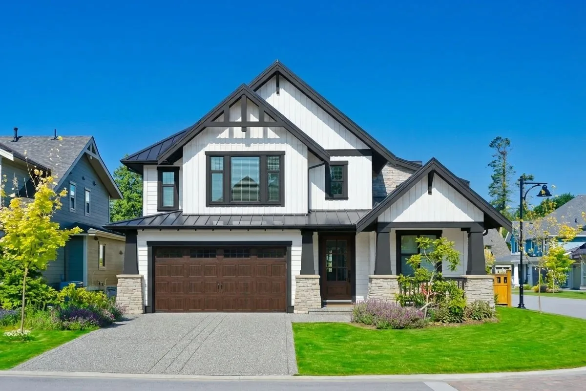 Modern farmhouse exterior with white board-and-batten siding, black trim, a dark metal roof, and a wood garage door, visualized in Renoworks.ai